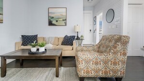 Un salon avec un canapé, un fauteuil, une table basse et un tableau accroché au mur.
