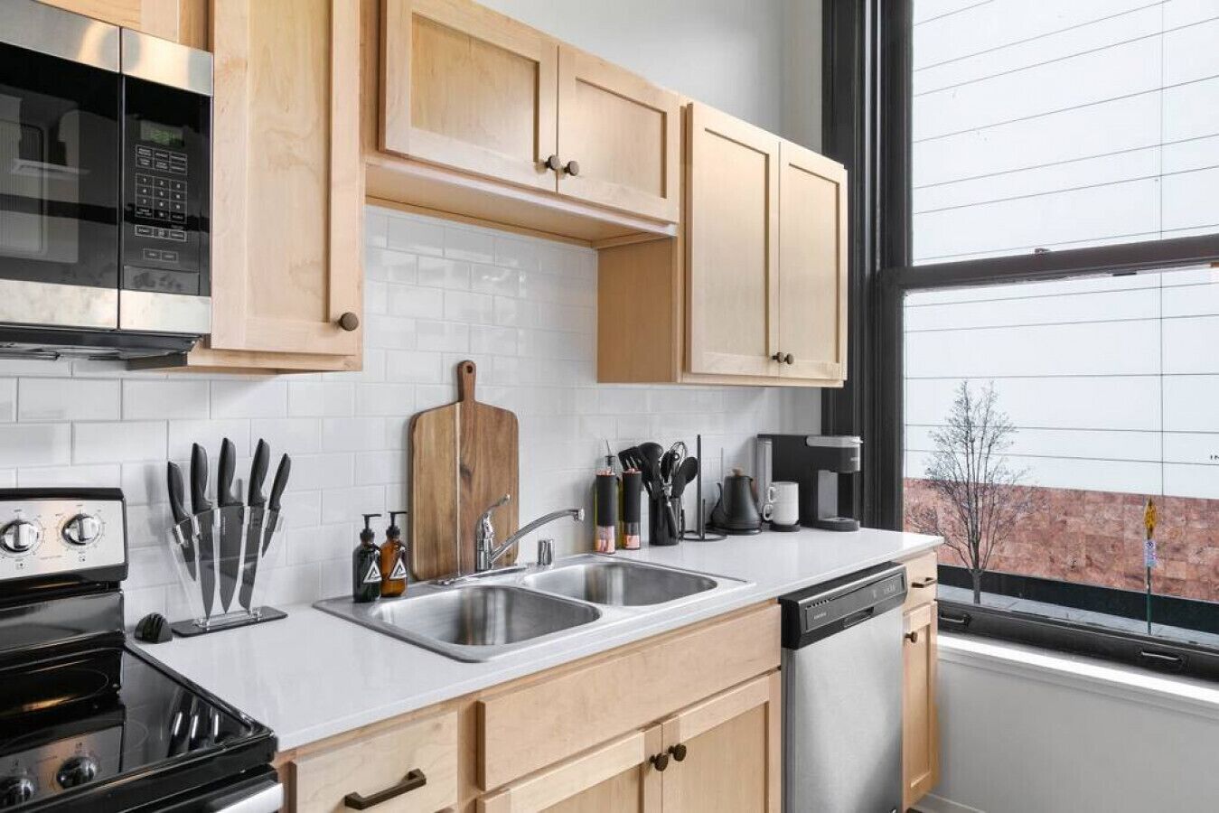 Una cocina moderna con armarios de madera, un lavamanos de acero inoxidable y una cafetera.