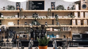 Un comptoir de café avec un tableau affichant le menu, des machines à café et une plante en pot.