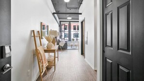 A hallway with a dark door, a wooden table with a lamp, and a chair. - Clean Upscale Hideout Close to Everything + WiFi (Spokane)