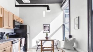 A modern kitchen with wooden cabinets, a black refrigerator, and a dining area with a round table and chairs. - Designer Loft Downtown with WiFi 210 (Spokane)