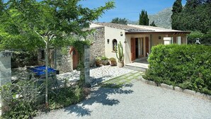 Une maison avec une façade en pierre, un toit en tuiles et une allée gravillonnée.
