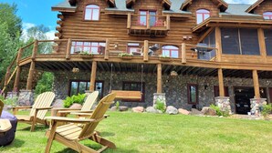 A large log cabin with multiple balconies, stone accents, and outdoor seating.