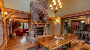 A spacious living area with a stone fireplace, wooden furniture, and a chandelier.