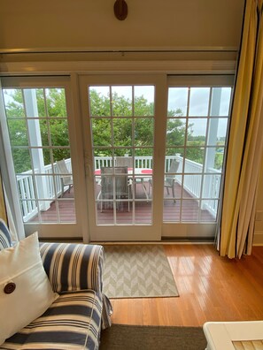 A room with a sliding glass door leading to an outdoor deck with a white railing and outdoor furniture. - Beaches, Golf, Pool and More (Rehoboth Beach)