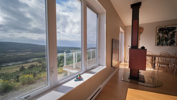 A modern interior with large windows offering a scenic view of a river and hills.