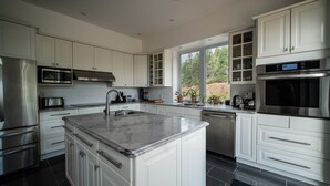 A modern kitchen with white cabinetry, stainless steel appliances, and a large island with a sink.