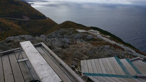 A wooden deck with benches overlooking a coastal landscape.