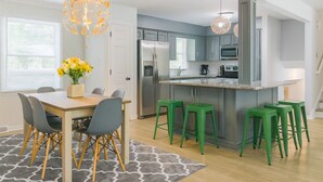 A modern kitchen with grey cabinets, a stainless steel refrigerator, and a central island with bar stools. - Pet Friendly • BBQ • Patio • Desired Location (Charlotte)