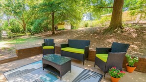 An outdoor patio with wicker furniture, a glass-top table, and potted plants. - Pet Friendly • BBQ • Patio • Desired Location (Charlotte)