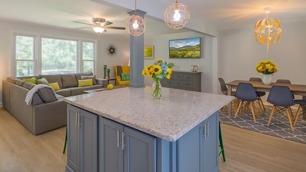 A modern kitchen with blue cabinets, a granite countertop, and a dining area with a table and chairs. - Pet Friendly • BBQ • Patio • Desired Location (Charlotte)