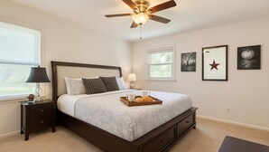 A bedroom with a bed, bedside tables, a ceiling fan, and framed artwork on the wall. - Pet Friendly • BBQ • Patio • Desired Location (Charlotte)