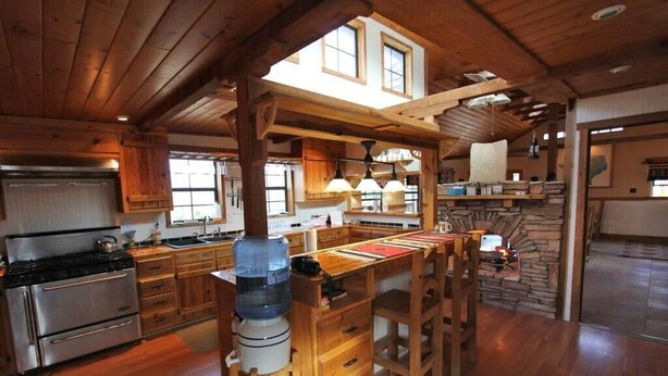 A spacious kitchen with wooden cabinets, a large island, and a water dispenser. - Big Bend Lodging at Ten Bits Ranch | Room #8 - The Courthouse (Terlingua)