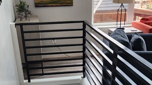 A staircase with a wooden finish, black railings, and a green door at the bottom. - Blue Haven Unit B All New - Downtown Moab! (Moab)
