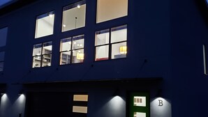 A modern building with multiple windows, a green door with a sign, and a garage. - Blue Haven Unit B All New - Downtown Moab! (Moab)