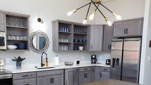 A modern kitchen with grey cabinets, a wooden dining table, and black chairs. - Blue Haven Unit B All New - Downtown Moab! (Moab)