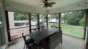 A covered outdoor deck with a table and chairs, a ceiling fan, and a view of a backyard with a deck and outdoor furniture. - Lazy Days Retreat (Hartfield)