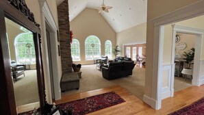 A spacious living area with a stone fireplace, a black leather sofa, and a ceiling fan. - Lazy Days Retreat (Hartfield)