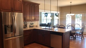 A modern kitchen with wooden cabinets, stainless steel appliances, and a central island. - Lazy Days Retreat (Hartfield)
