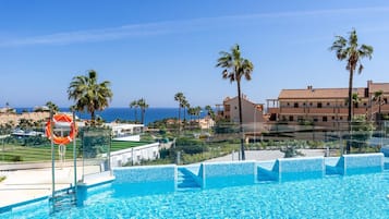 Une piscine équipée d’une bouée de sauvetage, bordée de palmiers et offrant une vue sur la mer.