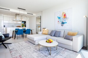 Una sala de estar moderna con un sofá, una mesa de centro y una zona de comedor con sillas.