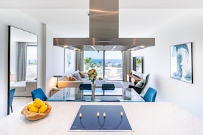 Habitació d'hotel moderna amb zona de menjador, una finestra gran amb vistes, una illa central amb suport per a espelma i un bol de limones.