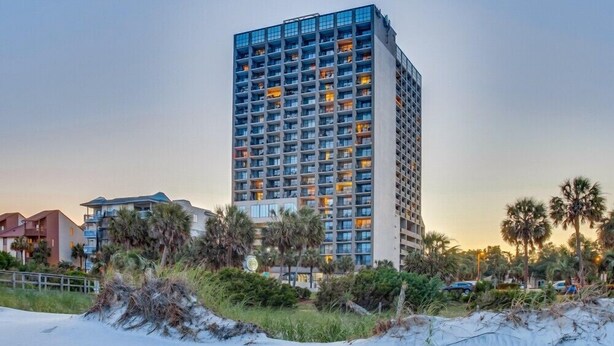 A tall hotel with multiple floors, balconies, and a beachside location.