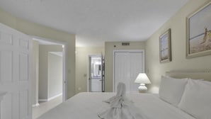 A hotel room with a large bed, a nightstand with a lamp, and a painting on the wall.