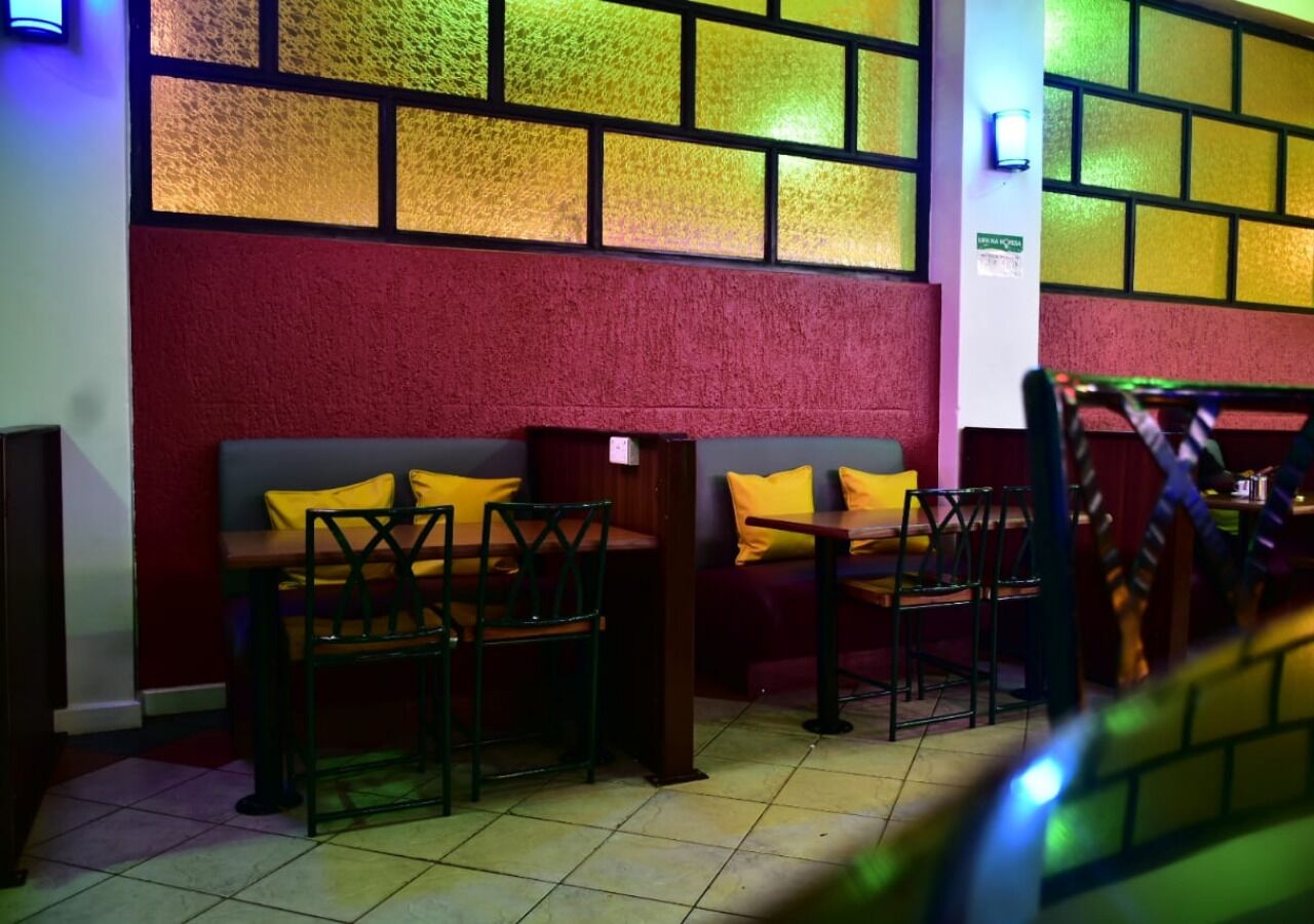 A seating area with two wooden benches and chairs, a red wall, and a tiled floor.