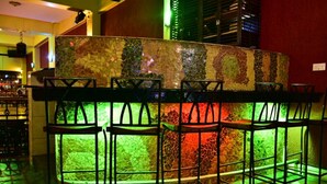 A bar area with a mosaic-tiled counter and black metal bar stools. - Klique Hotel (Eldoret)