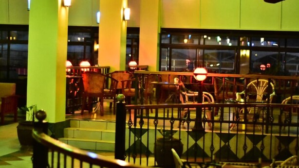 A restaurant with outdoor seating, tables, chairs, and a railing. - Klique Hotel (Eldoret)