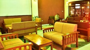 A lobby with wooden furniture, including sofas and tables, and a large wooden door. - Klique Hotel (Eldoret)