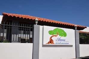 Welcome to the Arena condominium, featuring a metal gate and a tree graphic on the sign.