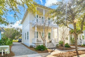 A two-story house with a front porch, a covered driveway, and a small garden area. - Golf Cart｜4bed, 3.5 bath｜Luxury 30A Getaway! (Santa Rosa Beach)