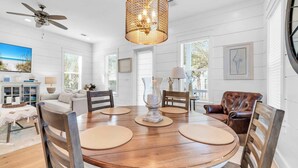 A dining area with a round wooden table, beige placemats, and a decorative centerpiece. - Golf Cart｜4bed, 3.5 bath｜Luxury 30A Getaway! (Santa Rosa Beach)