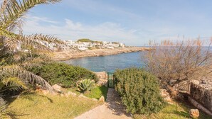 Un sentier côtier qui mène à une plage, avec des bâtiments blancs en arrière-plan.