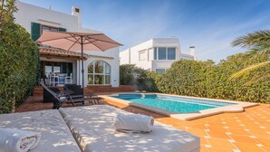 Un espace aménagé au bord de la piscine, comprenant un canapé, une table et des chaises, ainsi qu’une piscine.