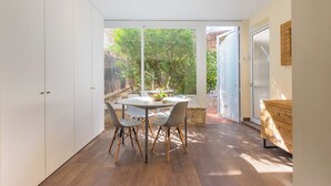Une cuisine moderne avec un coin repas, de grandes fenêtres et une vue sur l’extérieur.