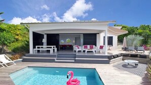 Une maison moderne dotée d’une piscine, d’un espace salon extérieur et d’un jardin tropical.