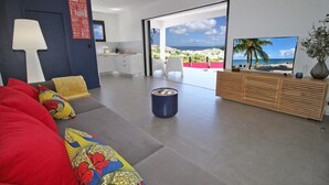 Un salon moderne avec un canapé, une table basse, un téléviseur et une vue sur l’extérieur.