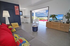 Een moderne woonkamer met een bank, een salontafel, een televisie en uitzicht op het landschap.