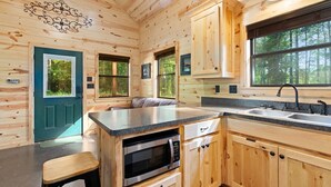 A wooden cabin interior with a kitchen area, including a countertop, sink, and cabinets. - Beautiful cabins with a pool in a peaceful setting (Broken Bow)