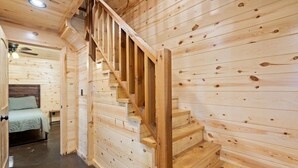 A wooden staircase in a cabin-style room with a bed and a ceiling fan. - Beautiful cabins with a pool in a peaceful setting (Broken Bow)