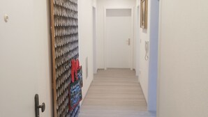 A hallway with a patterned wall, a door with a handle, a light fixture on the ceiling, and a rug on the floor. - Schwarzwaldmarie Ferienwohnung (löffingen)