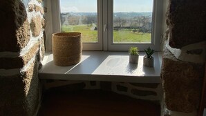 A room with a stone wall, a bench, a woven basket, and a small potted plant on a windowsill.