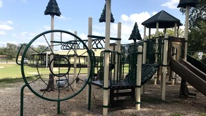 A playground with a slide, climbing structures, and a covered area. - Cozy Modern 1 Bed 1 Bath next to Park! (Van)