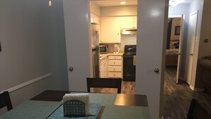 A dining area with a table set for two, a chair, and a mat on the floor. - Cozy Modern 1 Bed 1 Bath next to Park! (Van)