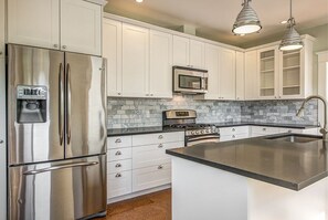 Una cocina moderna con electrodomésticos de acero inoxidable, armarios blancos y un salpicadero de mármol.
