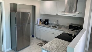 A modern kitchen with stainless steel appliances, white cabinets, and a granite countertop. - Escape to the Beach (Treasure Cay, North Abaco)