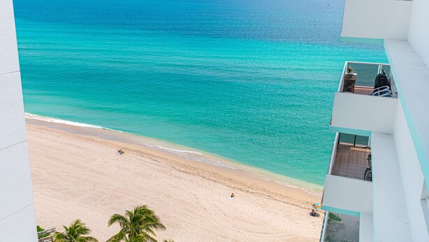 A beach view from a balcony with a clear ocean and sandy shore. - 2BR 2BA AMAZING NEWLY RENO BEACHFRONT APT W/BEACH VIEW (Hollywood)
